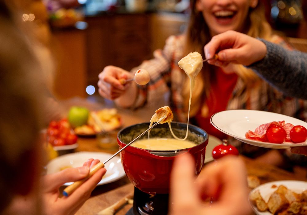 K&auml;sefondue mit Beilagen auf einem gedeckten Tisch