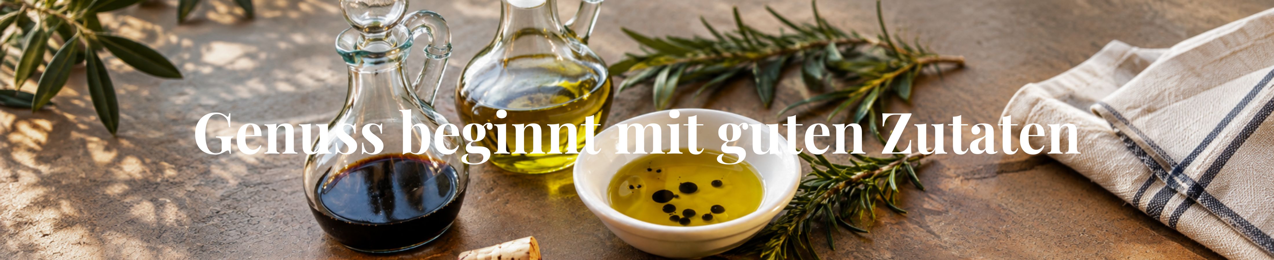 Olivenöl und Balsamico in Glaskaraffen mit Kräutern auf mediterranem Tisch