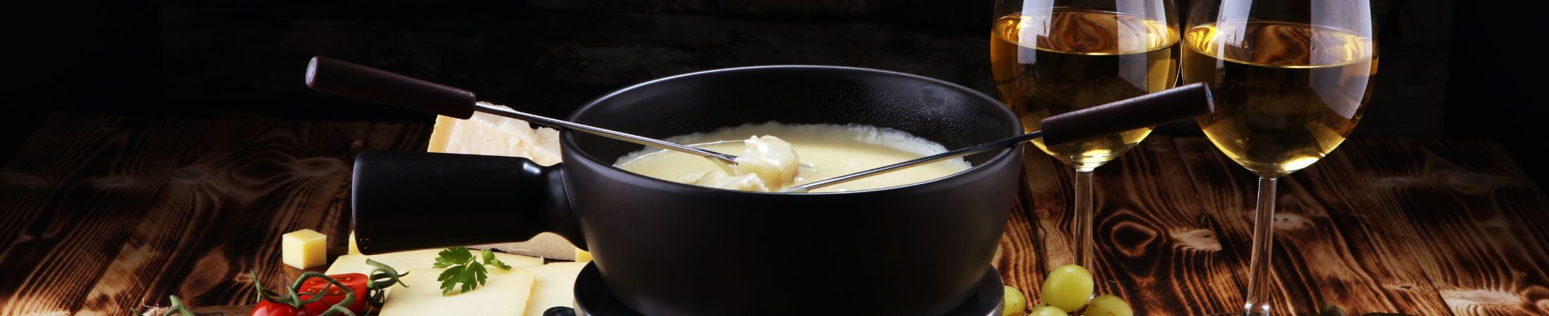 Käsefondue mit Zutaten auf einem gedeckten Tisch Käsefondue mit Zutaten auf einem gedeckten Tisch