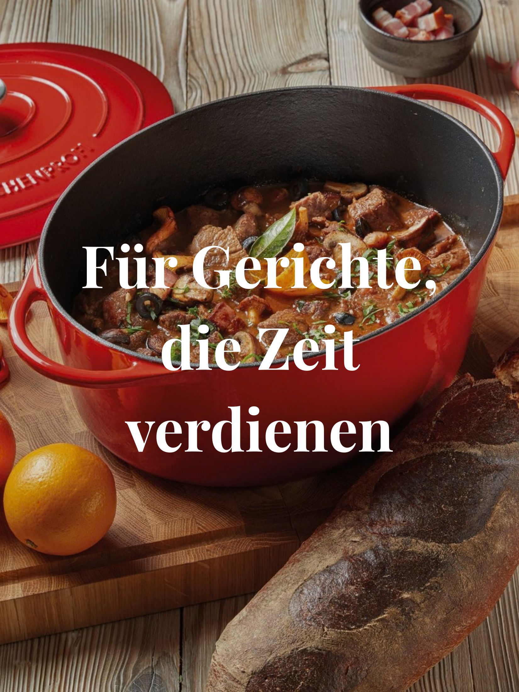 Roter Gusseisenbräter von KÜCHENPROFI mit Schmorgericht auf gedecktem Holztisch
